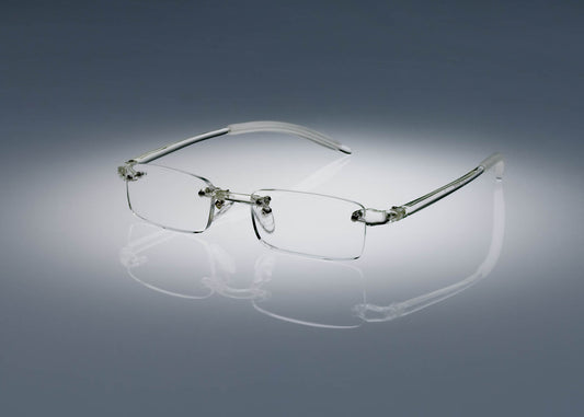 A pair of clear colored Ultimate Reading Glasses resting on a table, illuminated by a soft spotlight.