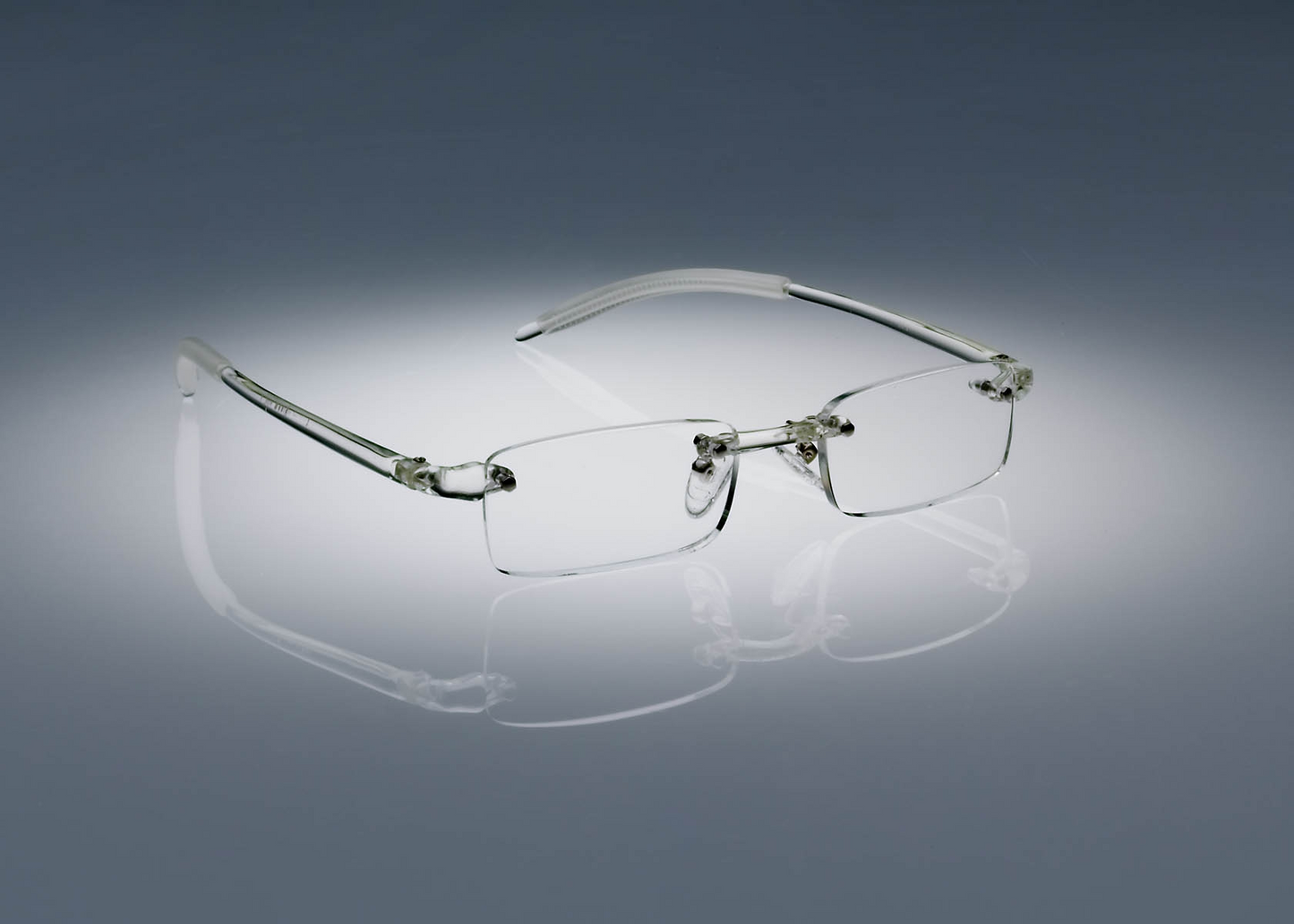 A pair of clear colored Ultimate Reading Glasses resting on a table, illuminated by a soft spotlight.