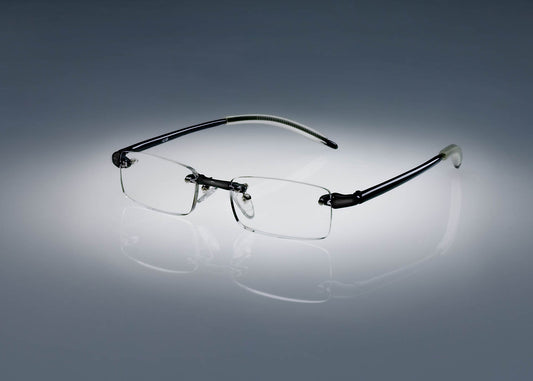 A pair of black colored Ultimate Reading Glasses resting on a table, illuminated by a soft spotlight.