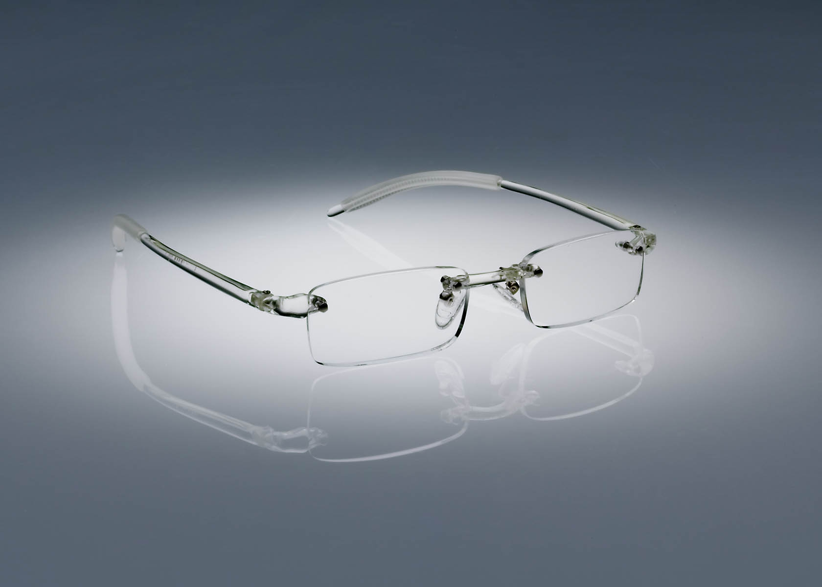 A pair of clear colored Ultimate Reading Glasses resting on a table, illuminated by a soft spotlight.