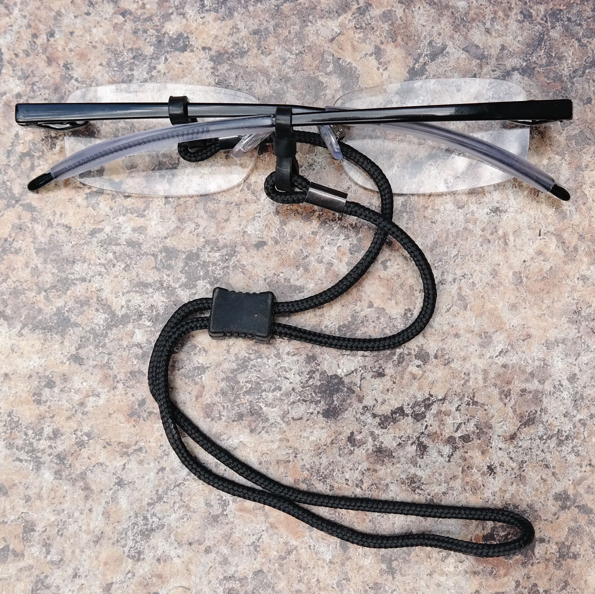 The Ultimate Reading Glasses lanyard wrapped around a pair of reading glasses, and resting on a table.