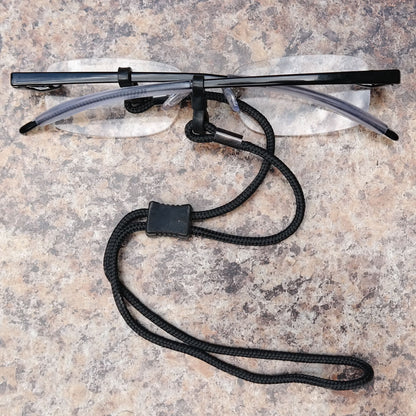 The Ultimate Reading Glasses lanyard wrapped around a pair of reading glasses, and resting on a table.